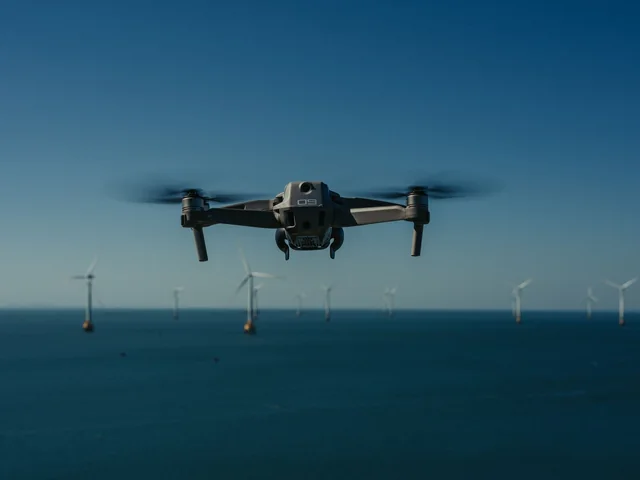 Illustrative drone in flight above the sea and wind turbines